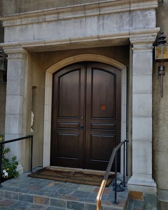 Arched stain-grade double front door in a limestone surround
