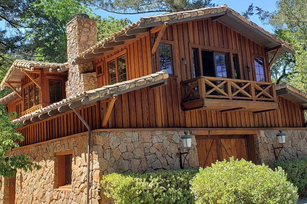 Redwood board-and-batten carriage house with a stone base, freshly stained