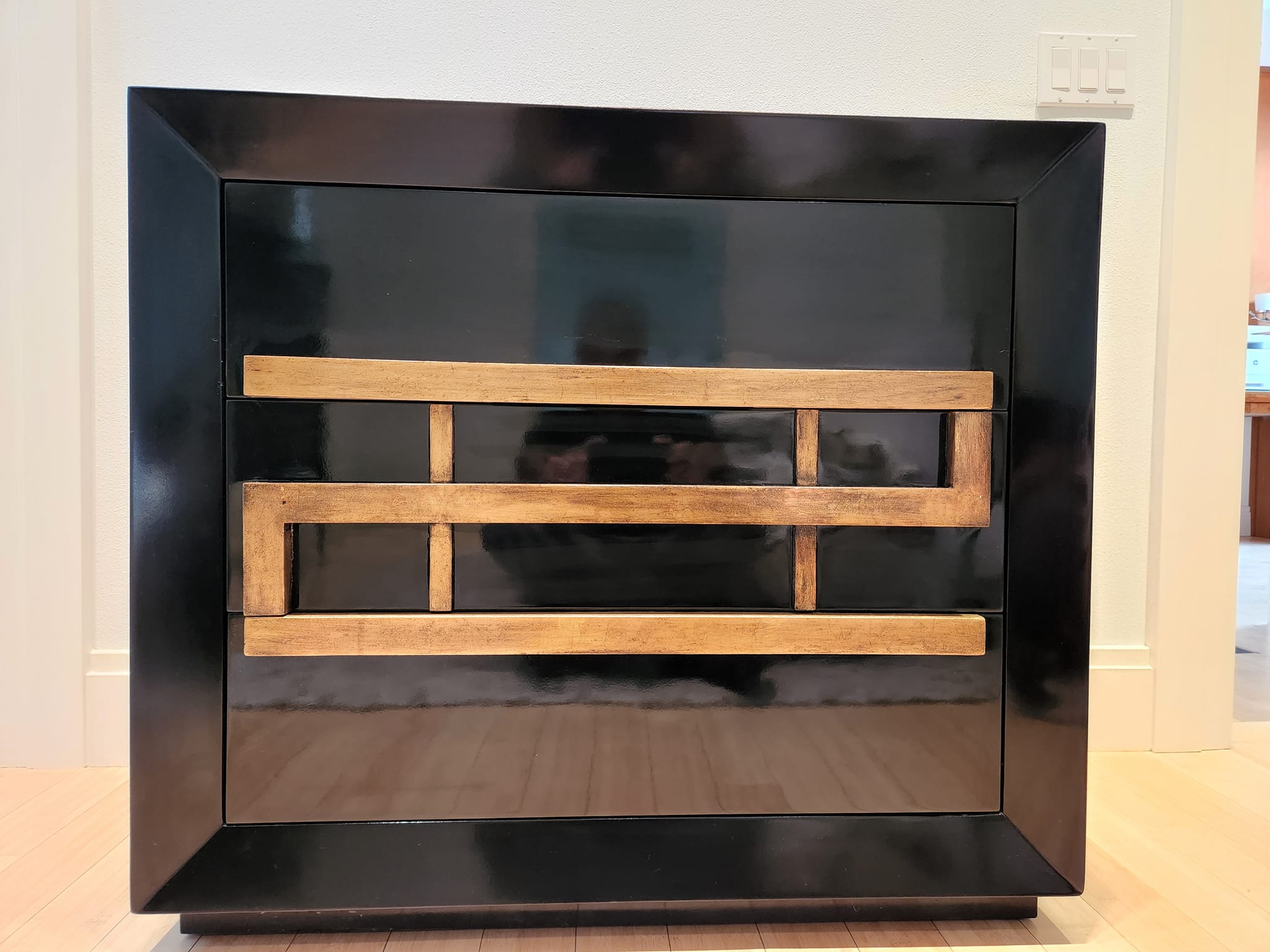 Black-lacquer cabinet piece refinished with gold trim detailing